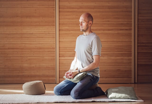 Mies istuu mindfulness-meditaatiossa